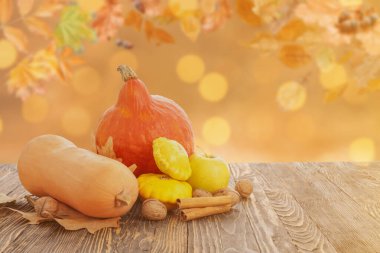 Taze balkabakları, kabaklar, fındıklar ve sonbahar yaprakları dışarıda, ahşap masada.