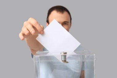 Açık arkaplanda oy sandığının yakınındaki genç adam, yakın plan