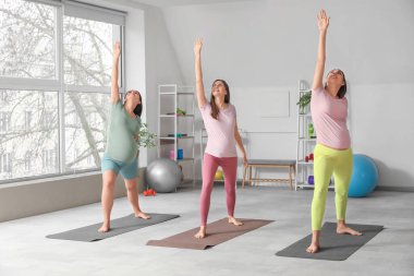 Güzel, genç, sportif, hamile kadınlar spor salonunda esniyorlar.