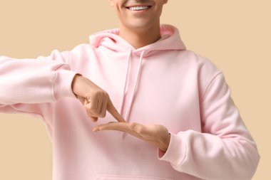 Bej arka planda işaret dili kullanan genç sağır ve dilsiz adam.