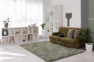 Yeşil kanepe ve raf üniteleri üzerinde glukofon olan oturma odasının içinde.