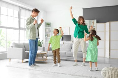 Mutlu ebeveynler ve küçük çocukları evde dans ediyor.