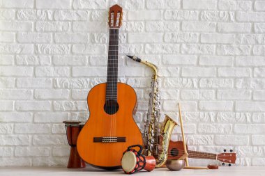 Beyaz tuğla duvarın yanında farklı müzik aletleri