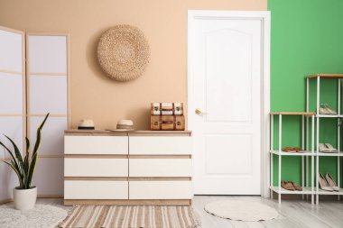 Katlanan ekran, ayakkabı standı ve koridorda şapka ve bavul dolu çekmeceler.