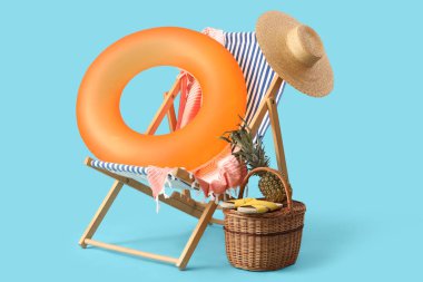 Şişirilebilir yüzük, güverte sandalyesi ve sepet, mavi arka planda ananas ve parmak arası terlik. Seyahat kavramı