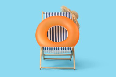 Mavi arka planda şişirilebilir halka ve güverte sandalyesi. Seyahat kavramı