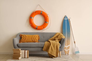 Oturma odasında minderli, ekose, sörf tahtalı, kürekli ve can simidi yüzüklü rahat bir kanepe.