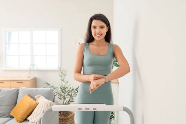 Akıllı, genç bir bayan evdeki koşu bandında nabzını kontrol ediyor.