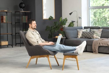 Dizüstü bilgisayarlı genç erkek öğretmen evde online ders veriyor.