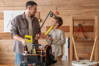 Mutlu baba ve farklı enstrümanlarla küçük oğlu atölyede sehpa hazırlıyorlar.