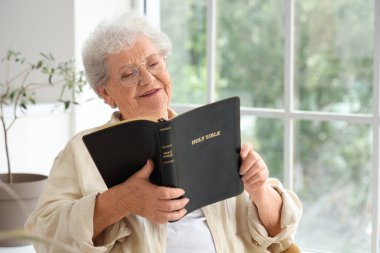 Evde İncil okuyan kıdemli bir kadın.