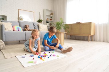 Evde yerde plastikten heykel yapan küçük çocuklar.