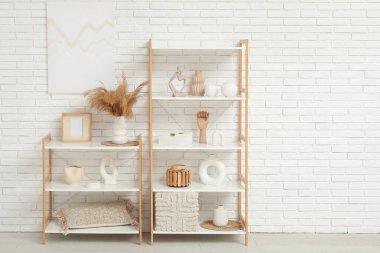 Dekorlu raf ünitesi ve beyaz tuğla duvarın yanındaki oda.