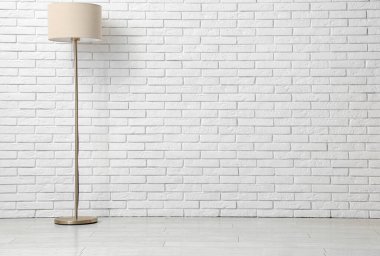 Beyaz tuğla duvarın yanında yer lambası var.