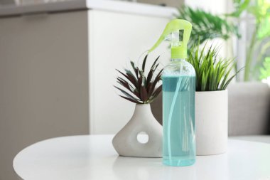 Mutfaktaki masada bitkilerle birlikte bir şişe aroma spreyi, yakın plan.