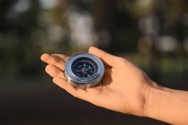 Gün batımında ormanda pusulası olan kadın, yakın plan.