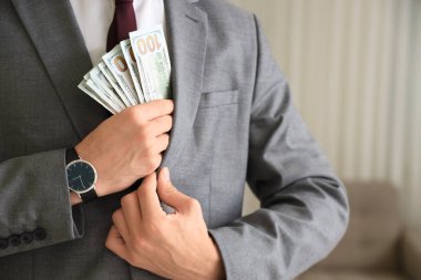 Genç işadamı rüşveti ofiste ceketinde saklıyor, yakın plan. Yolsuzluk kavramı