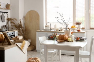 Sonbahar dekorlu, tezgahlı ve yemek masalı aydınlık mutfağın içi.