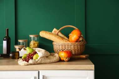 Mutfaktaki yeşil duvarın yanında içinde yemek ve şarap olan balkabakları.