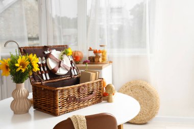 Mutfaktaki yemek masasında sonbahar dekoru ve ayçiçekli piknik sepeti.