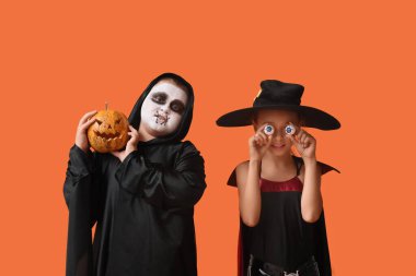 Cadılar Bayramı için giyinmiş çocuklar turuncu arka planda