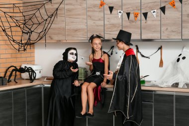 Cadılar Bayramı için giyinmiş çocuklar mutfakta konuşuyor.