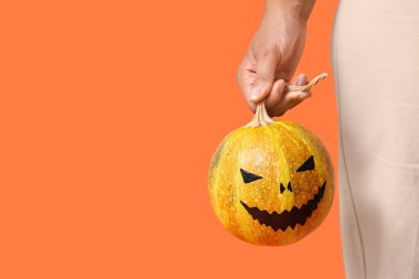 Turuncu arka planda Cadılar Bayramı balkabağı olan güzel Afro-Amerikalı kadın, yakın plan.