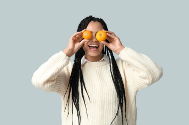 Gri arka planda balkabakları olan güzel, mutlu, Afro-Amerikalı bir kadın.