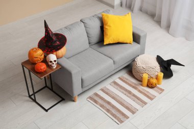 Oturma odasının içinde kanepe, Cadılar Bayramı balkabağı ve cadı şapkaları var.