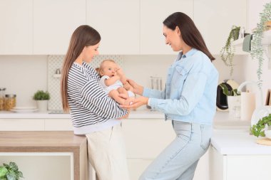 Mutfakta küçük bebekleri olan genç lezbiyen çift.