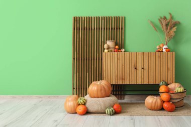 Evdeki yeşil duvarın yanında farklı kabaklardan oluşan hasır sepetli ahşap tuvalet.