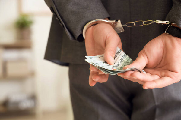 Наручники бизнесмену со взяткой в офисе, вид сзади. Концепция коррупции