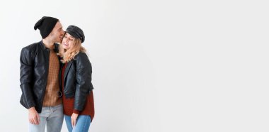 Happy young couple in warm autumn clothes on light background with space for text