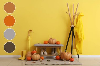 Yağmurluk askısı, ayakkabılı bank, şemsiye ve koridorun iç tarafında sonbahar yapraklı balkabağı. Farklı renk desenleri