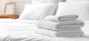 Yatakta beyaz yumuşak havlular yığını  