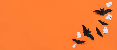 Cadılar Bayramı partisi için kağıt yarasalar ve hayaletler turuncu arka planda ve metin için yer var.