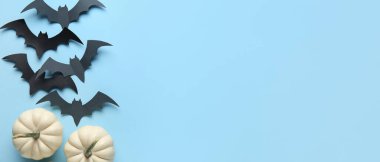 Cadılar Bayramı partisi için kağıt yarasalar ve taze balkabakları açık mavi arka planda ve metin için yer var