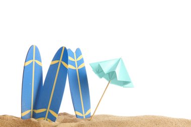 Beyaz arka planda kum üzerinde şemsiyesi olan mini sörf tahtaları
