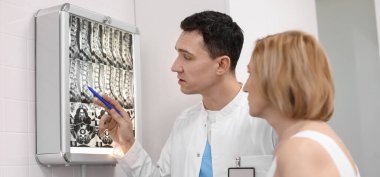 Doktor, klinikte hastanın omurga MRI taramasını gösteriyor.