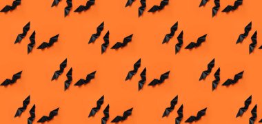 Cadılar Bayramı partisi için turuncu arka planda bir sürü siyah kağıt yarasa