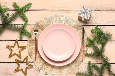 Köknar dalları, hediye kutusu ve bej ahşap arka planda çatal bıçaklı şenlik masası.