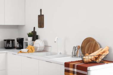 Kahve makinesi, çoklu fırın ve çatal bıçaklı beyaz mutfak tezgahları.