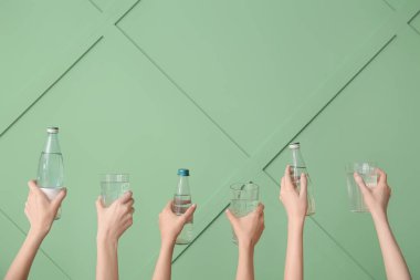 Yeşil arka planda temiz suyla bardakları ve şişeleri tutan kadınlar