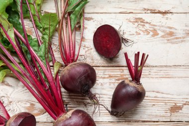 Açık ahşap arka planda yeşil yapraklı taze pancarlar.