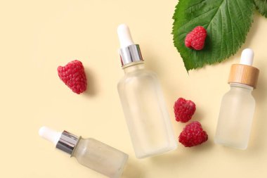 Sarı arka planda kozmetik ahududu yağı şişeleri