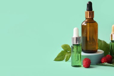 Mavi arka planda kozmetik ahududu yağı şişeleriyle dekoratif podyum