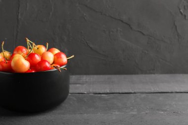 Siyah ahşap masada tatlı sarı kirazlı kase