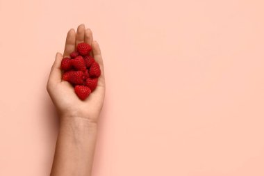 Pembe arka planda taze ahududu tutan kadın.