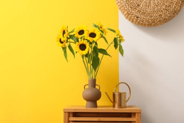 Çekmecede ayçiçekli vazo ve sulama kutusu var.