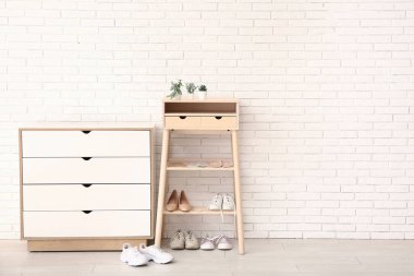 Ayakkabı askısı, şık ayakkabılar ve ortopedik tabanlar, odada hafif tuğladan duvarın yanında.